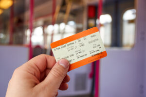 A person's hand holding an orange train ticket