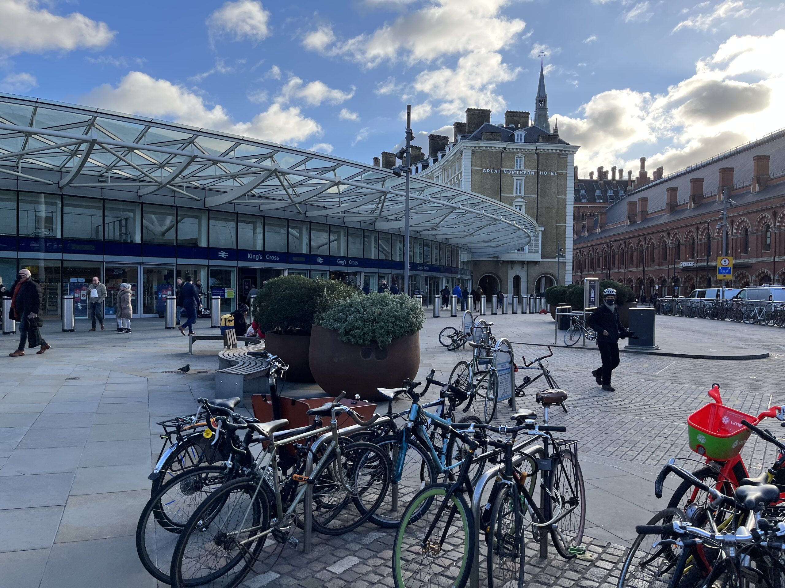 Bikes stacked in foreground with London King's Cross and St Pancras railway / Tube stations in the background.