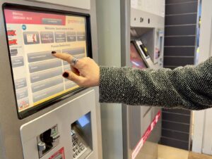 Person selecting ticket on ticket machine in a train station