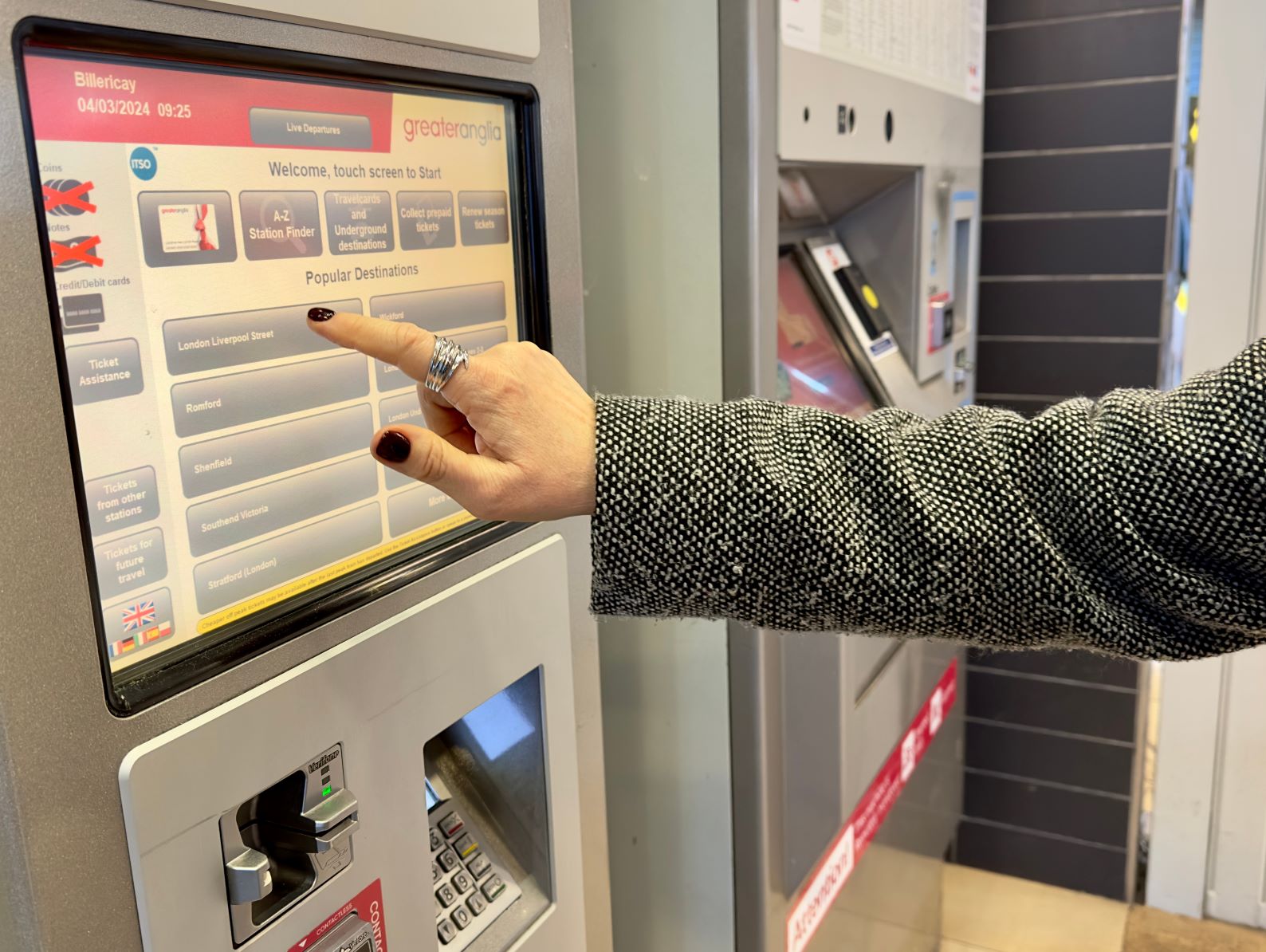 Person selecting ticket on ticket machine in a train station