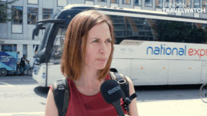 Woman with red hair and wearing a red top being interviewed on the street in London