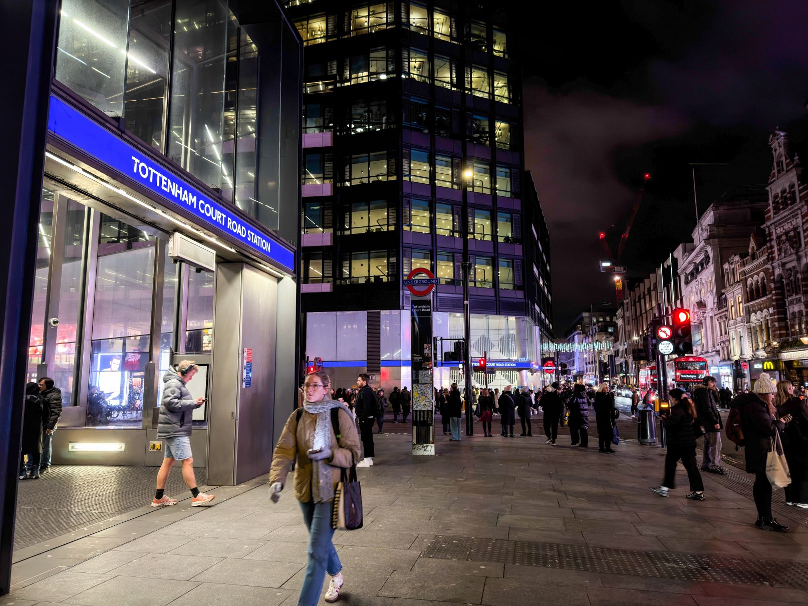Pedestrians outside Tottenham Court station on a dark evening