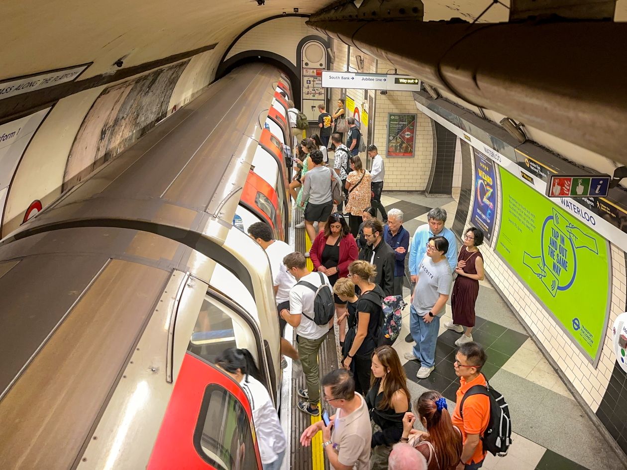 A busy tube platform with a train pulled in and passengers getting on and off