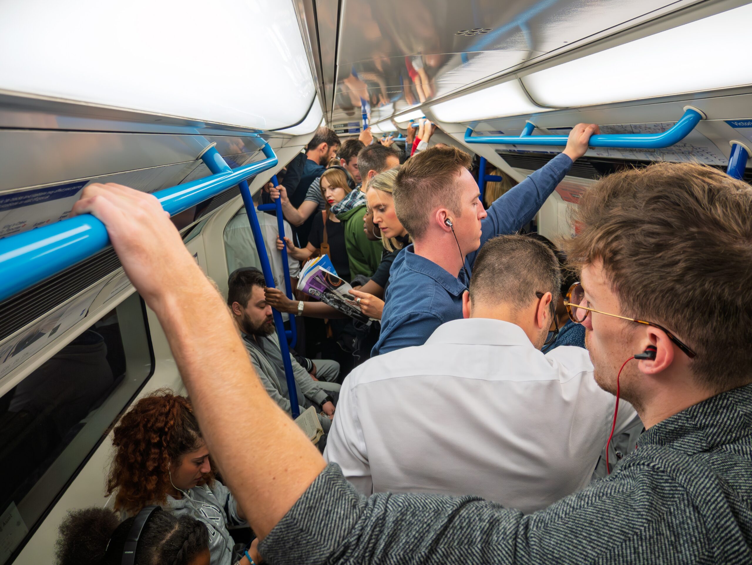 The image shows passengers standing inside a very busy tube carriage
